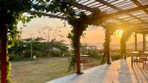 a pergola with a table and a bench in a garden at Lobster Bay Lombok in Awang