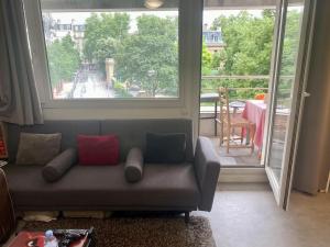 a living room with a couch and a large window at Beau appart à balcon vue Tour Eiffel & parking in Paris