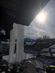 una vista invernale sugli edifici innevati e sul sole di Kur- und Ferienhotel Haser a Oberstaufen