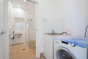 ein Badezimmer mit Waschmaschine und Waschbecken in der Unterkunft Austral warm 4br house with parking&WiFi in Austral