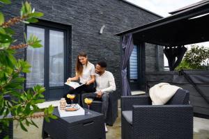 a man and a woman sitting on a patio at TOPAZE Nuitée Romantique avec Jacuzzi in Moyvillers