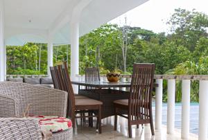 a patio with a table and chairs on a porch at Ocean Blue Bay in Anse Volbert Village