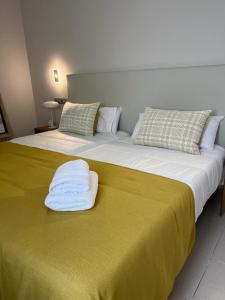 een groot bed met een gele deken en kussens bij OMBÚLAFUENTE in Puerto de Mogán