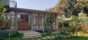 una casa con una puerta roja en un jardín en Serene meadows villa en Bangalore