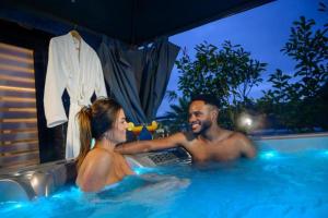 a man and a woman sitting in a hot tub at TOPAZE Nuitée Romantique avec Jacuzzi in Moyvillers