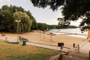 uma praia de areia com guarda-sóis e um parque infantil em Słoneczna em Sieraków