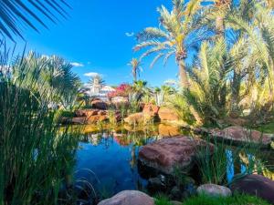 einen Garten mit Palmen und einem Teich in der Unterkunft Eden Lodges & SPA in Marrakesch