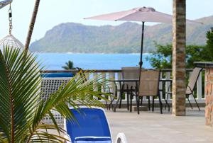 a patio with a table and chairs and an umbrella at Ocean Blue Bay in Anse Volbert Village