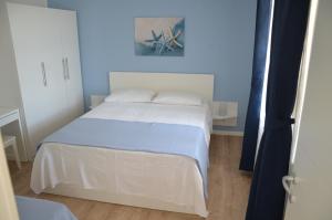 Cama blanca en habitación con pared azul en Apartments Ostanek en Portorož