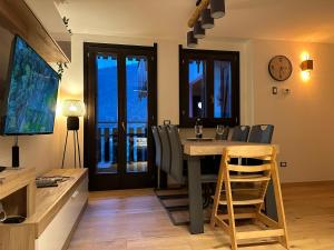 une salle à manger avec une table, des chaises et une horloge dans l'établissement SnowLodge Valmalenco, à Caspoggio