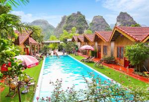 um resort com uma piscina com montanhas ao fundo em For You Homestay em Ninh Binh