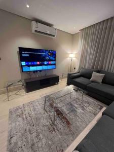 a living room with a couch and a flat screen tv at Modern 3 Bedroom Flat in Riyadh