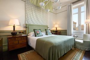 um quarto com uma cama, uma cadeira e uma janela em Rocco Forte Villa Igiea em Palermo