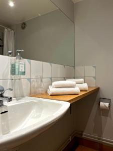 ein Badezimmer mit einem Waschbecken, einem Spiegel und Handtüchern in der Unterkunft Aspenäs Herrgård in Lerum