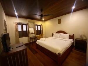 - une chambre avec un lit et une télévision dans l'établissement somvang khily guesthouse 宋旺吉利 酒店, à Luang Prabang