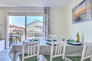 a dining room with a table and chairs and a balcony at Appartement T3 moderne au Grau du roi in Le Grau-du-Roi