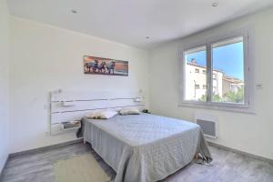 biała sypialnia z łóżkiem i oknem w obiekcie Appartement T3 moderne au Grau du roi w mieście Le Grau-du-Roi