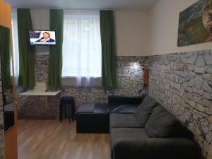 a living room with a couch and a tv at Kid Família Panzió Balatonszárszó in Balatonszárszó