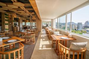 a restaurant with wooden tables and chairs and windows at Mercure Phuket Patong Journeyhub in Patong Beach