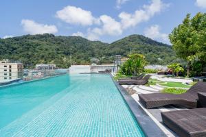 a swimming pool on top of a building with mountains in the background at Mercure Phuket Patong Journeyhub in Patong Beach