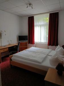 a bedroom with a bed and a desk and a window at Hotel Zum Goldenen Löwen in Merseburg