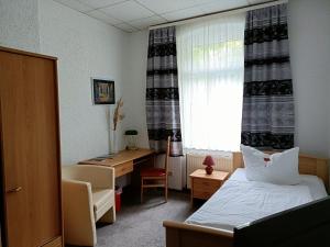 Schlafzimmer mit einem Bett, einem Schreibtisch und einem Fenster in der Unterkunft Hotel Zum Goldenen Löwen in Merseburg