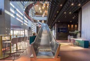 an escalator in a building with chairs and tables at Barceló Malaga in Málaga