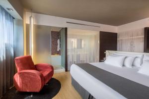 a bedroom with a bed and a red chair at Barceló Malaga in Málaga