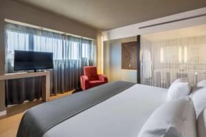 a hotel room with a bed and a flat screen tv at Barceló Malaga in Málaga