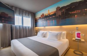 a bedroom with a large white bed with a painting on the wall at Barceló Malaga in Málaga