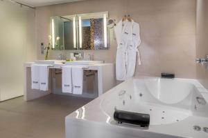 a white bathroom with a tub and a sink at Barceló Malaga in Málaga
