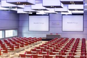 a lecture hall with red chairs and two screens at Barceló Malaga in Málaga