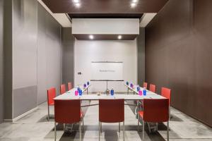 a conference room with a white table and red chairs at Barceló Malaga in Málaga