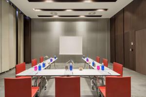 a conference room with a long table and red chairs at Barceló Malaga in Málaga