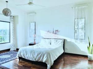 um quarto com uma cama com lençóis brancos e pisos em madeira em Romantic Suite by the Lake em Cyberjaya