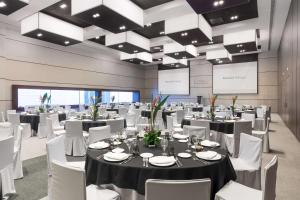 a banquet hall with tables and white chairs at Barceló Malaga in Málaga +37 photos