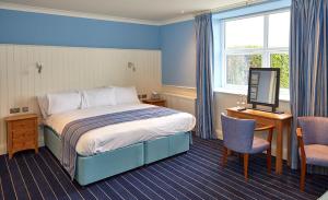 a hotel room with a bed and a desk and a television at Trearddur Bay Hotel in Trearddur