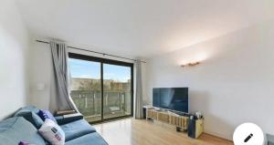 ein Wohnzimmer mit einem blauen Sofa und einem großen Fenster in der Unterkunft Modern Spacious 2-Bed Apartment in London in Bromley