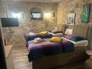 three beds in a room with stone walls at Elena Rooms Split in Split