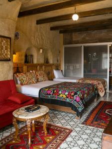 1 dormitorio con 2 camas y sofá rojo en Canela Cave Hotel - Cappadocia, en Göreme
