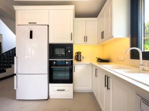 a kitchen with white cabinets and a white refrigerator at CAPELLA VİLLAS in Fethiye