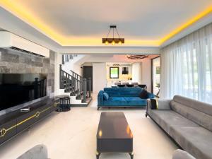 a living room with a couch and a tv at CAPELLA VİLLAS in Fethiye
