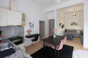 a kitchen and living room with a table and pink chairs at Feel Meteora 1BD luxury apt in Kalabaka