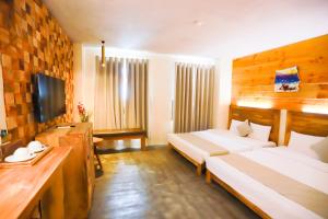 a hotel room with two beds and a television at Rustic Hotel Quy Nhon Powered by ASTON in Quy Nhon