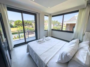 a bedroom with a white bed and large windows at CAPELLA VİLLAS in Fethiye +25 photos