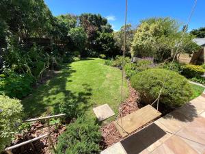 a garden with a swing in the yard at Baha Sanctuary House - 3 Bedroom House with Pool in Plettenberg Bay