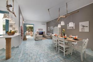 una cucina e un soggiorno con tavolo e sedie di I Tre Golfi - Villa Iride a San Vito lo Capo