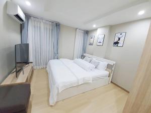 a bedroom with a large white bed and a flat screen tv at Family Condo-style in Phra Nakhon Si Ayutthaya