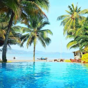 una piscina accanto a una spiaggia con palme di Lamsai AC Sea House a Ko Yao Noi