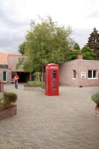 una cabina de teléfono rojo en un camino de ladrillo en Room in Apartment - Condo Gardens Leuven - Student Studio Single en Leuven